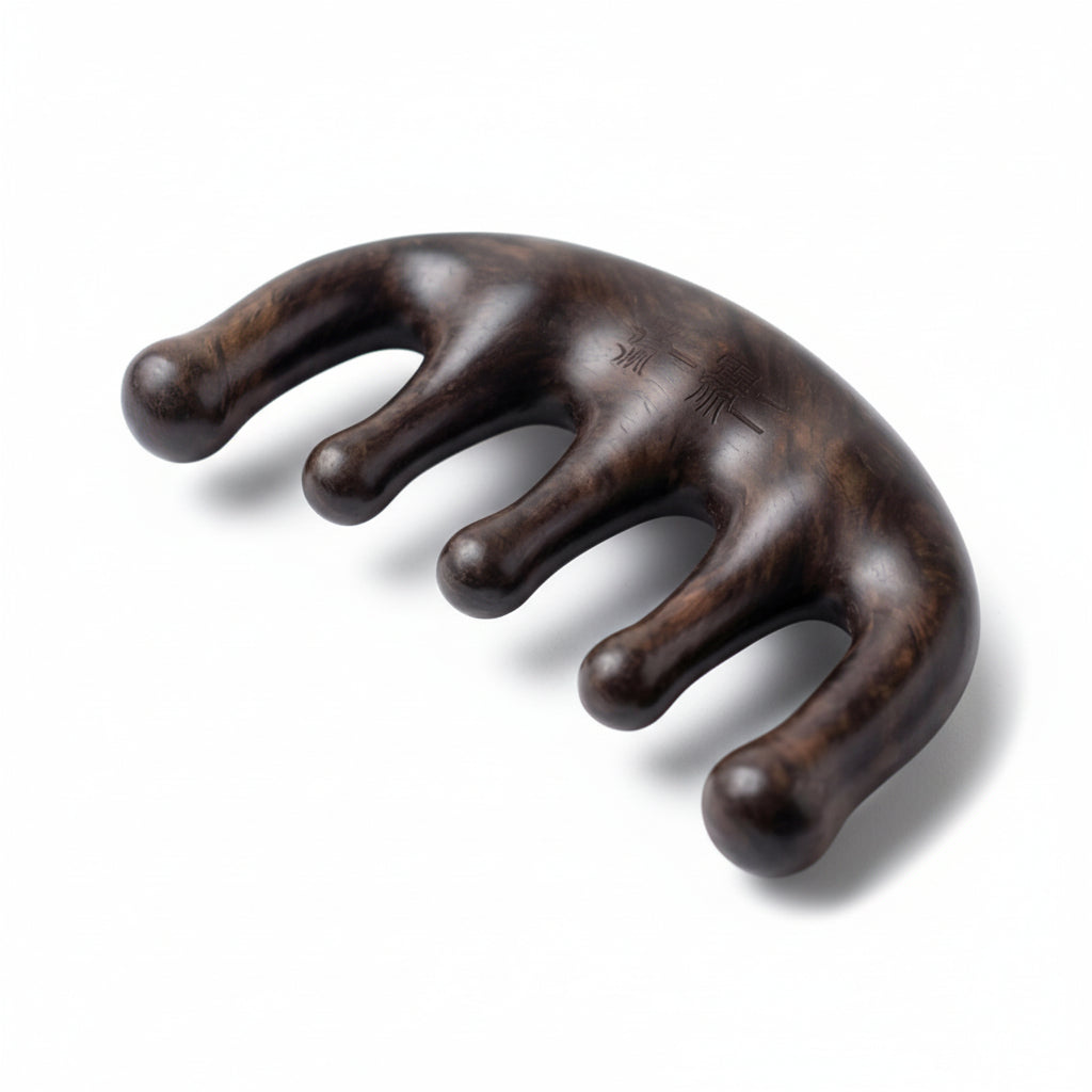 Black sandalwood scalp and neck massage comb with curved pressure point design on white background