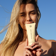 Woman holding SPF 30 Natural Body Sunscreen close to her face, highlighting sun protection for sensitive and eczema-prone skin.